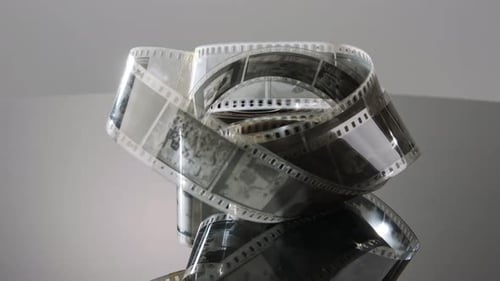 35mm film negative rotating on a reflective surface. Studio shot