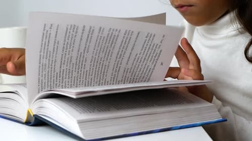 Child Reading a Large Book Indoors