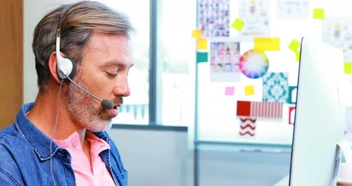 Männliche Führungskraft arbeitet am Computer mit Headset