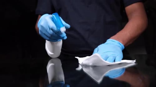 Person Cleaning Surface With Spray and Cloth