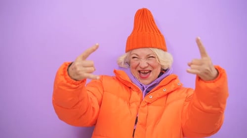 Active Mature Woman Shows Rock and Roll Hand Gesture, Having Fun, Isolated Background in Studio