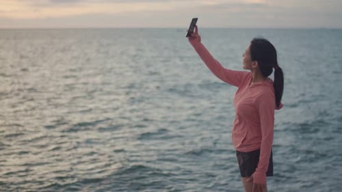 Woman on Beach Taking Video with Cell Phone