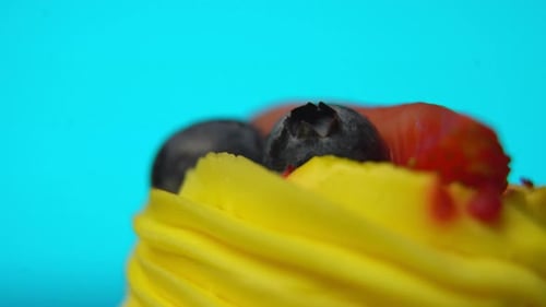 Yellow Cupcake Topped with Berries on Blue Backdrop