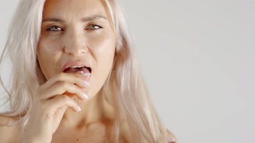 Seductive Blonde Woman Chewing Gum in Studio