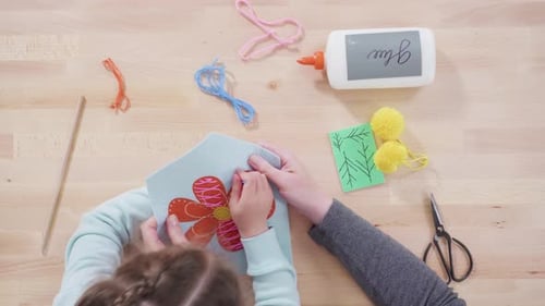 Flat lay. Little girl learning how to sew with her mother at the craft table.