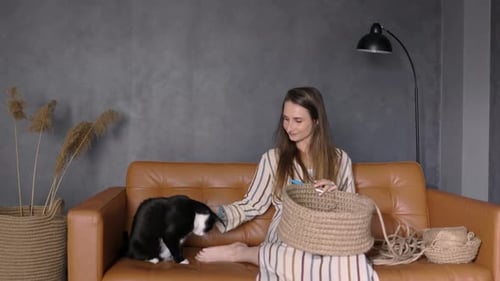 Woman Crocheting with a Cat on Couch at Home