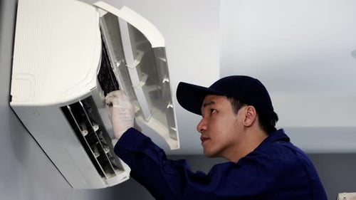 Technician Servicing Air Conditioner in Home