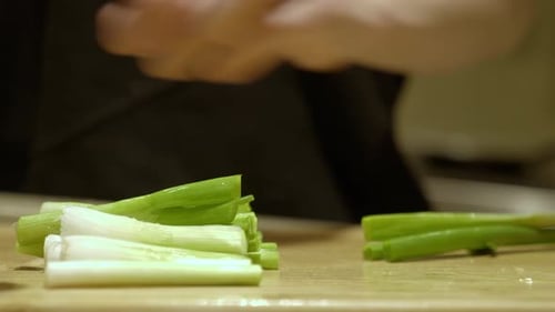 Cutting Scallion (Spring Onion) By A Knife On Wooden Board. Close Up