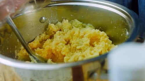 Mashed Potatoes Being Mixed in Shiny Metal Pot