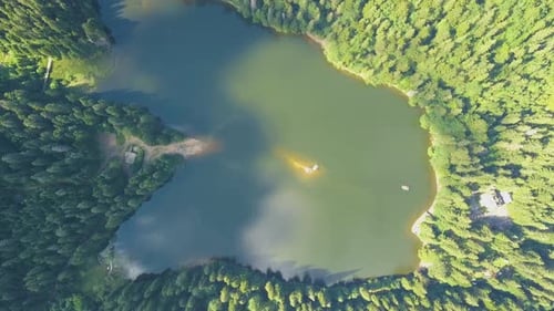 Top down aerial view of big lake with clear blue water between high mountain hills covered with