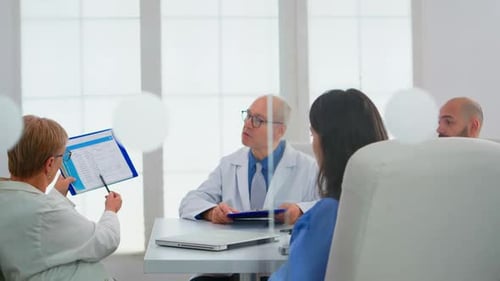 Elderly Doctor Having Medical Conference in Hospital Meeting Room