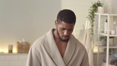 Young Man Sprays Cologne in Bathroom