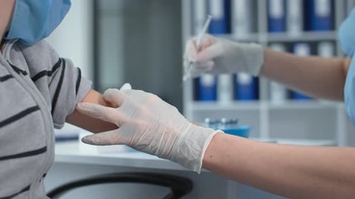 Pandemic Close Up Hands of Medical Nurse in Safety Gloves is Making a Vaccine Injection to Little