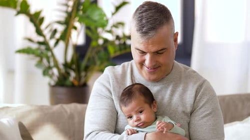 Loving Father Holding Newborn Baby at Home