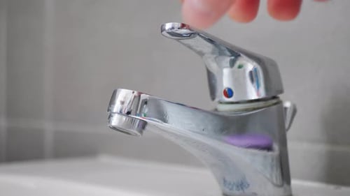 Water Flowing From Chrome Faucet Into Clean Basin