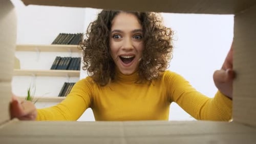 Excited Woman Opening Cardboard Box with Anticipation
