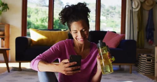Woman Using Phone and Drinking Water at Home