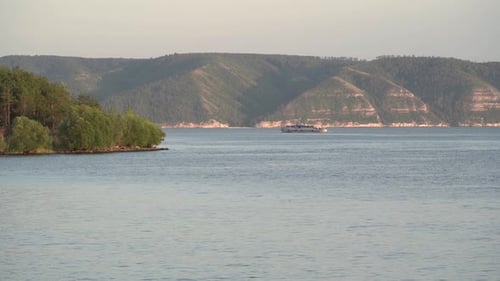 Passenger ship sailing on the river near the mountains.