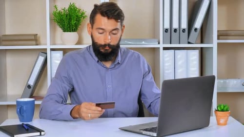 Man with Card Types on Laptop in Office