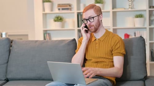 Man Talks on Phone While Using Laptop at Home
