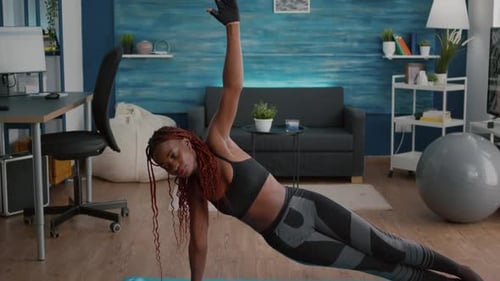 Flexible Black Woman Warming on Yoga Map in Living Room Standing in Side Plank