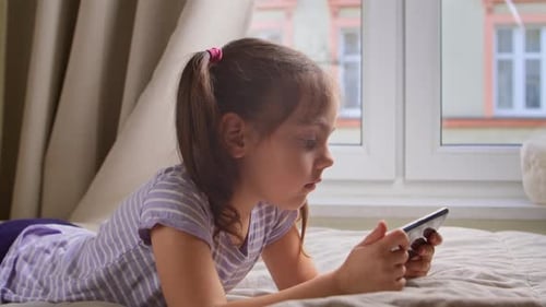 Girl Lies on Bed Using Smartphone