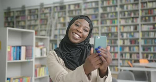 Smiling Woman Using Smartphone in Library Setting