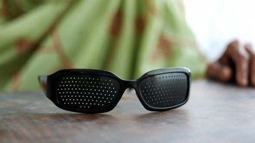 Close-up of Pinhole Glasses and Adult Hands