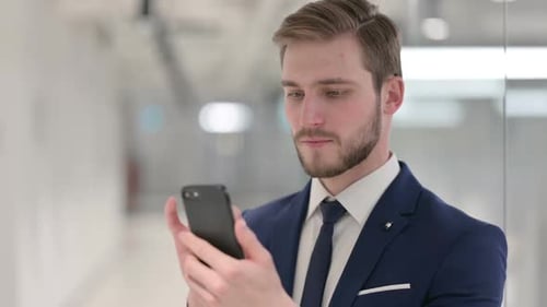 Young Adult Man Using Smartphone in Office