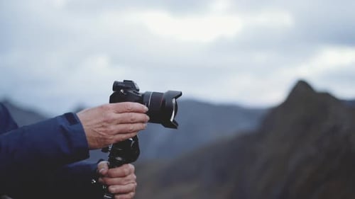 Photographer Prepares Camera in Mountain Landscape