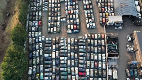 Luftaufnahme des großen Parkplatzes des Schrottplatzes mit Reihen von weggeworfenen kaputten Autos