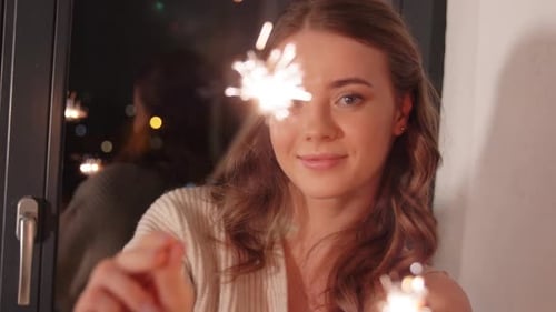 Smiling Woman Celebrates with Sparklers at Night