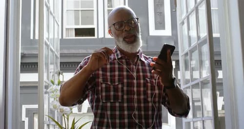Senior Man Dancing to Music by Open Window