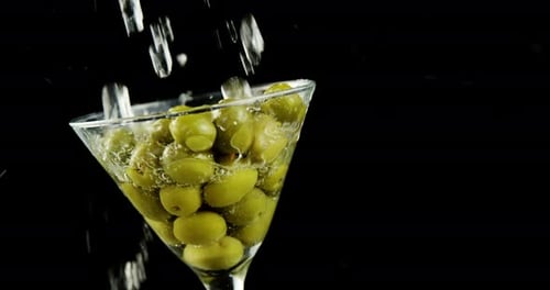 Cocktail Glass Filled with Green Olives being Poured