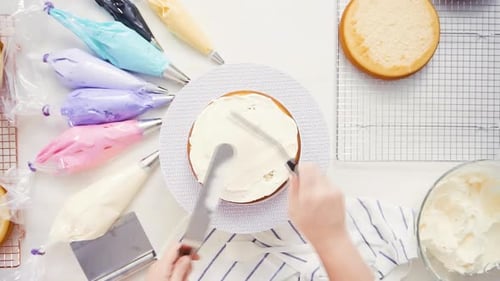 Step by step. Top view. Pastry chef stacking cake layers with buttercream frosting between to create