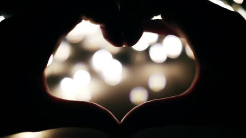 Hands Make Heart Shape Against Bokeh Lights