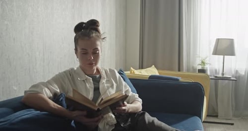 Woman Relaxes on Couch Reading a Book
