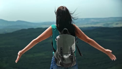 Successful Female Traveler Celebrating Win on Top of Mountain