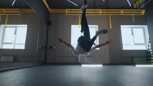 Exercice acrobatique sur le système TRX dans un gymnase Jeune femme athlétique pendue tête baissée et tourbillonne