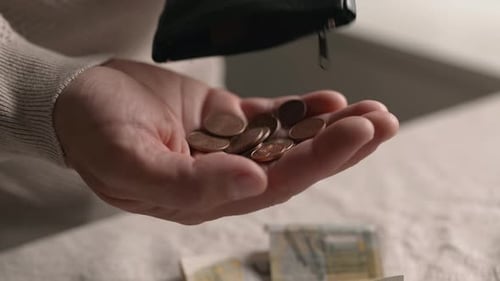 Coins pouring from wallet into hand