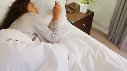 Woman in Bed Looking at Phone