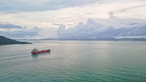 Drone flying towards one industrial ship sailing in sea at sunrise. Chinese cargo ship.