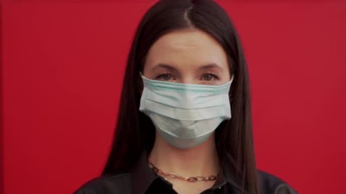 Woman with Face Mask Against Red Wall
