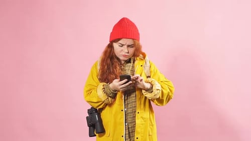 Woman Uses Phone with Binoculars on Pink Background