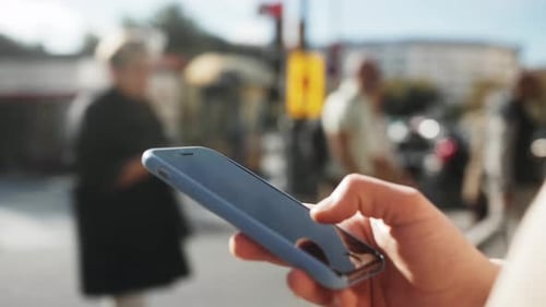 Hand Using Smartphone on City Street
