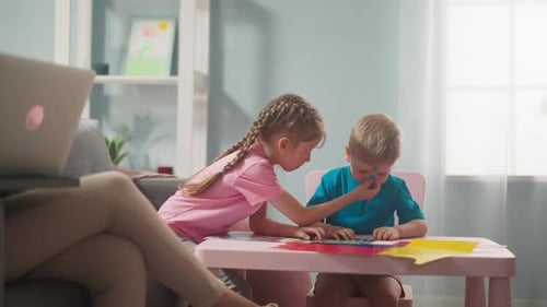 Children put stickers on each other at table