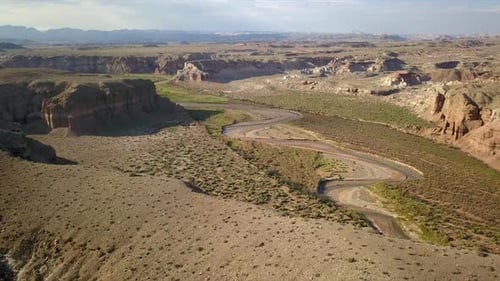 Desert aerial view flying backwards over hilltops viewing Muddy Creek