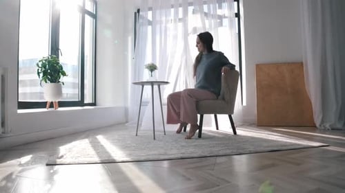 Woman Moving Chair in Bright Room