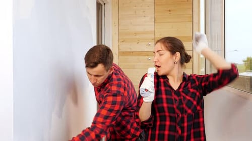 Woman Sings and Dances While Tired Man Paints Wall at Home