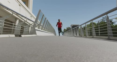 Man Running Toward Camera on Urban Bridge